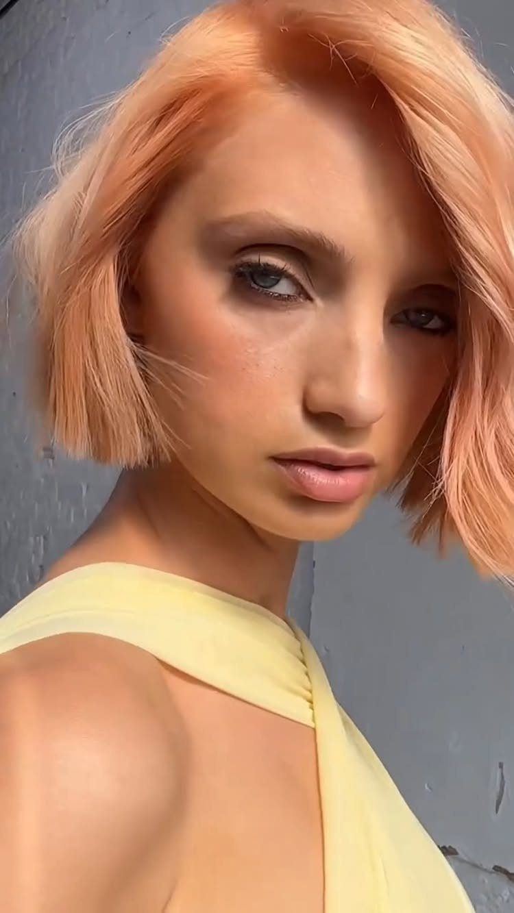 Woman with a chin-length copper bob and pale yellow top