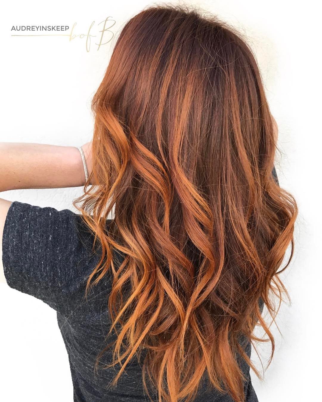 Long wavy brown hair blends into copper strands against a white background.