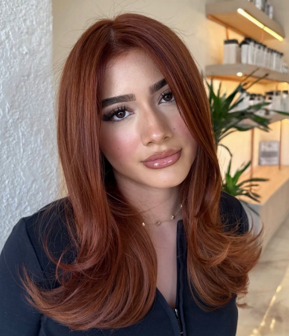 Woman with long natural-looking copper auburn hair styled in smooth, curled layers