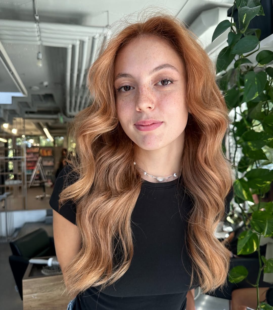 Woman with long, wavy light copper-orange hair in a bright salon