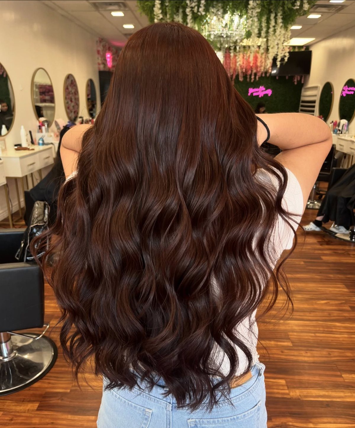 Long wavy auburn brown hair shown from behind in a salon