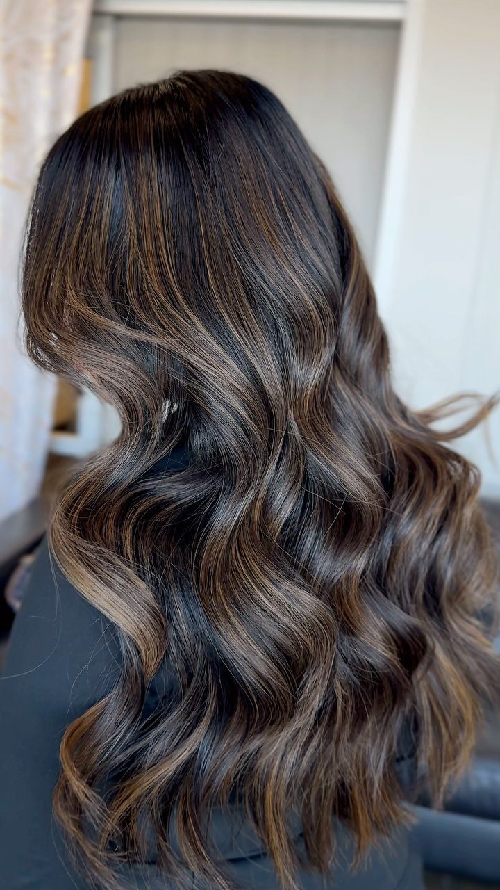 Wavy brunette hair with dark roots and softly blended blonde balayage highlights