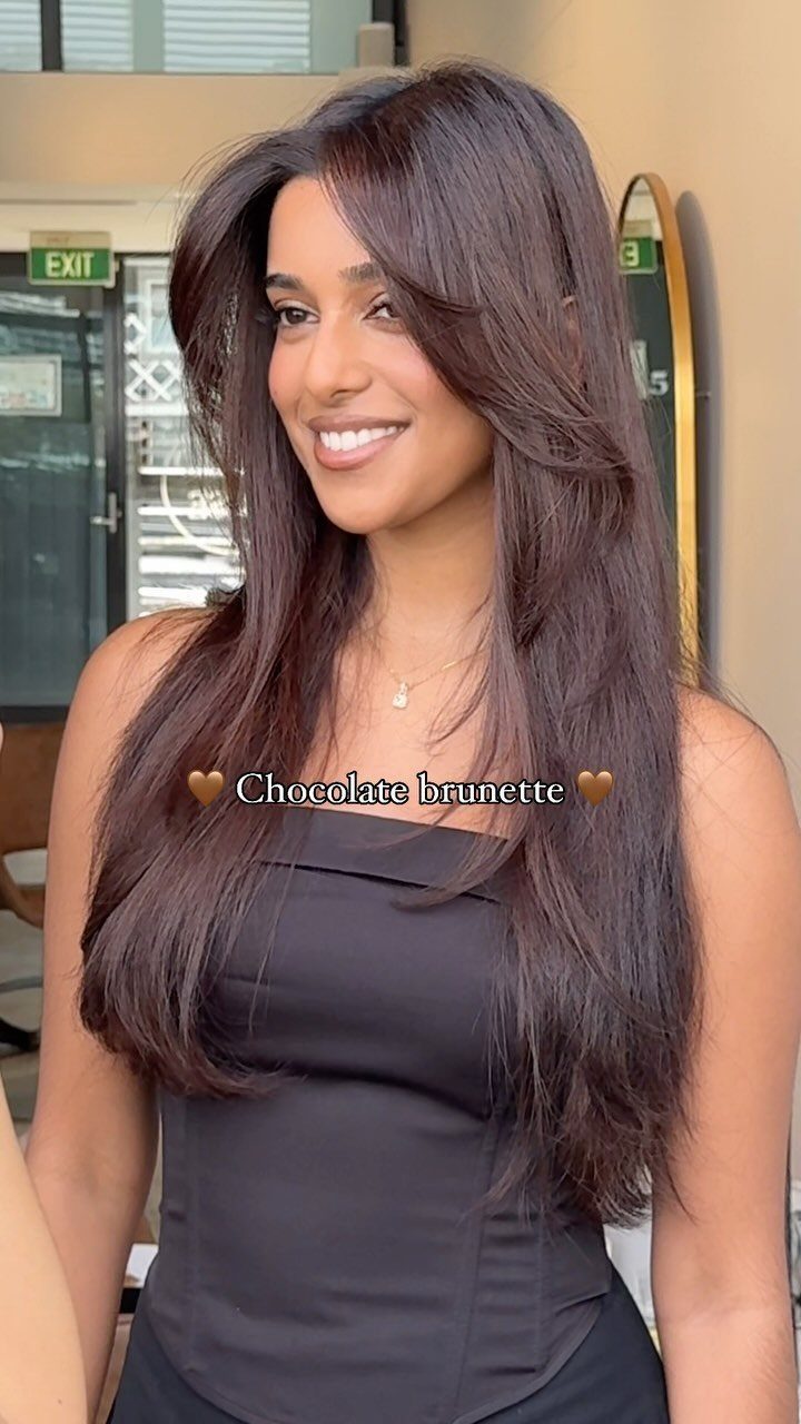 Woman showing long, deep chocolate brown hair with subtle reddish highlights