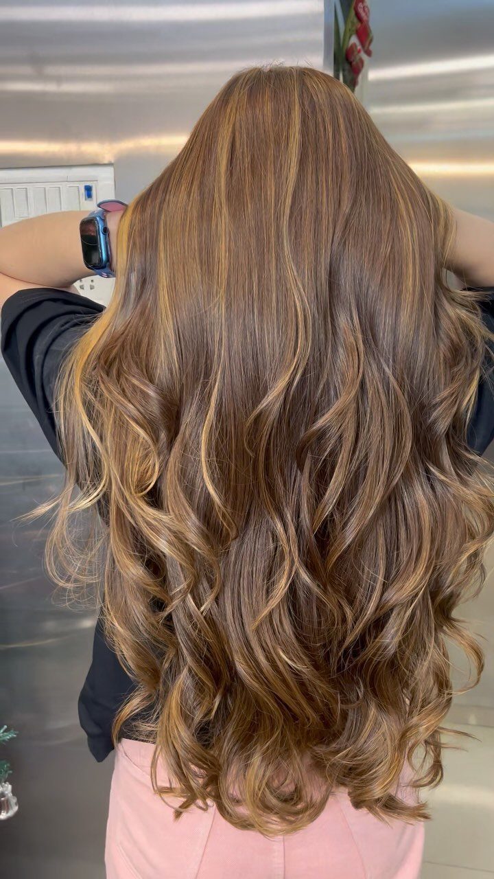 Long copper-brown hair falls in glossy curls down a salon client's back