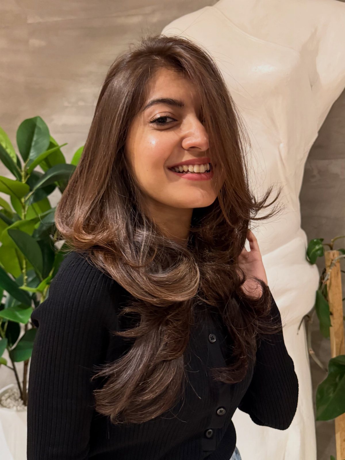 Woman showing layered brown hair with warm honey-colored highlights