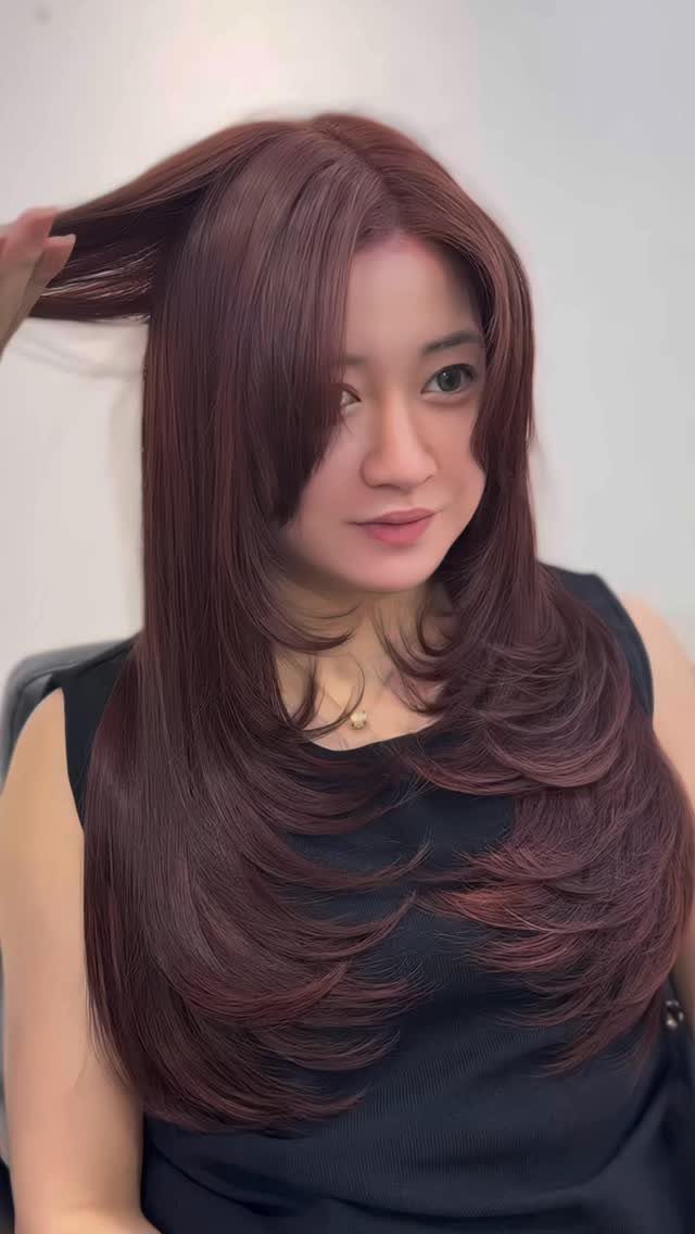 Woman showing long, layered mahogany brown hair with a rich reddish cast