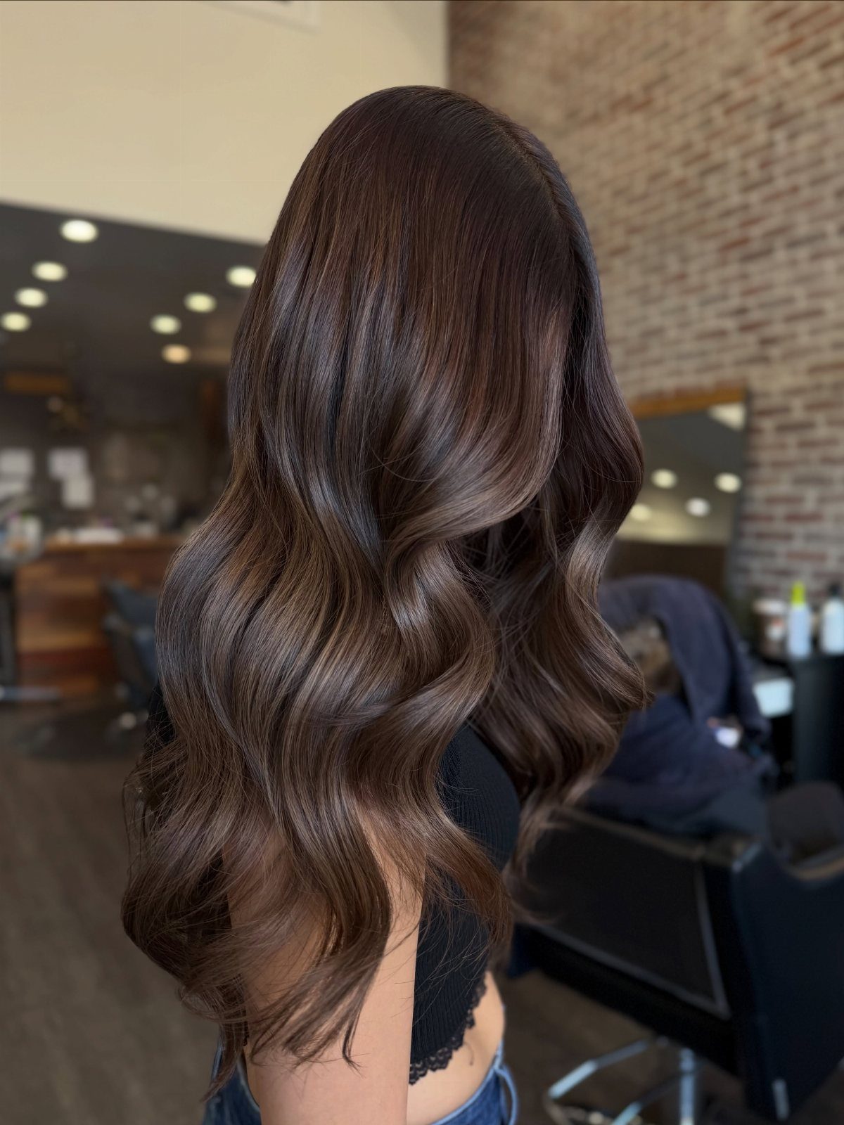 Wavy dark mocha brown hair with subtle lighter highlights in a salon