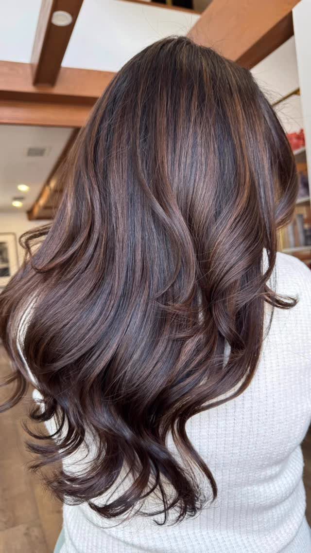 Long brunette hair with subtle lighter balayage ribbons and loose curls