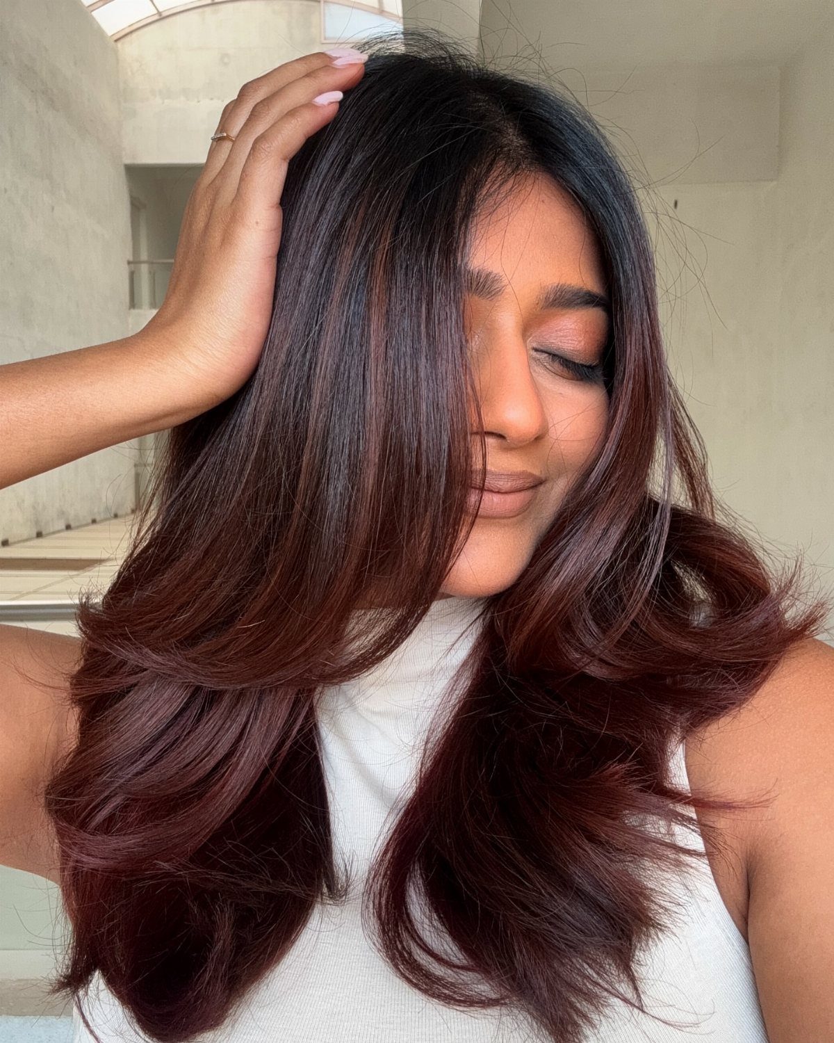 Woman with long layered brunette hair and subtle warm reddish-brown pieces