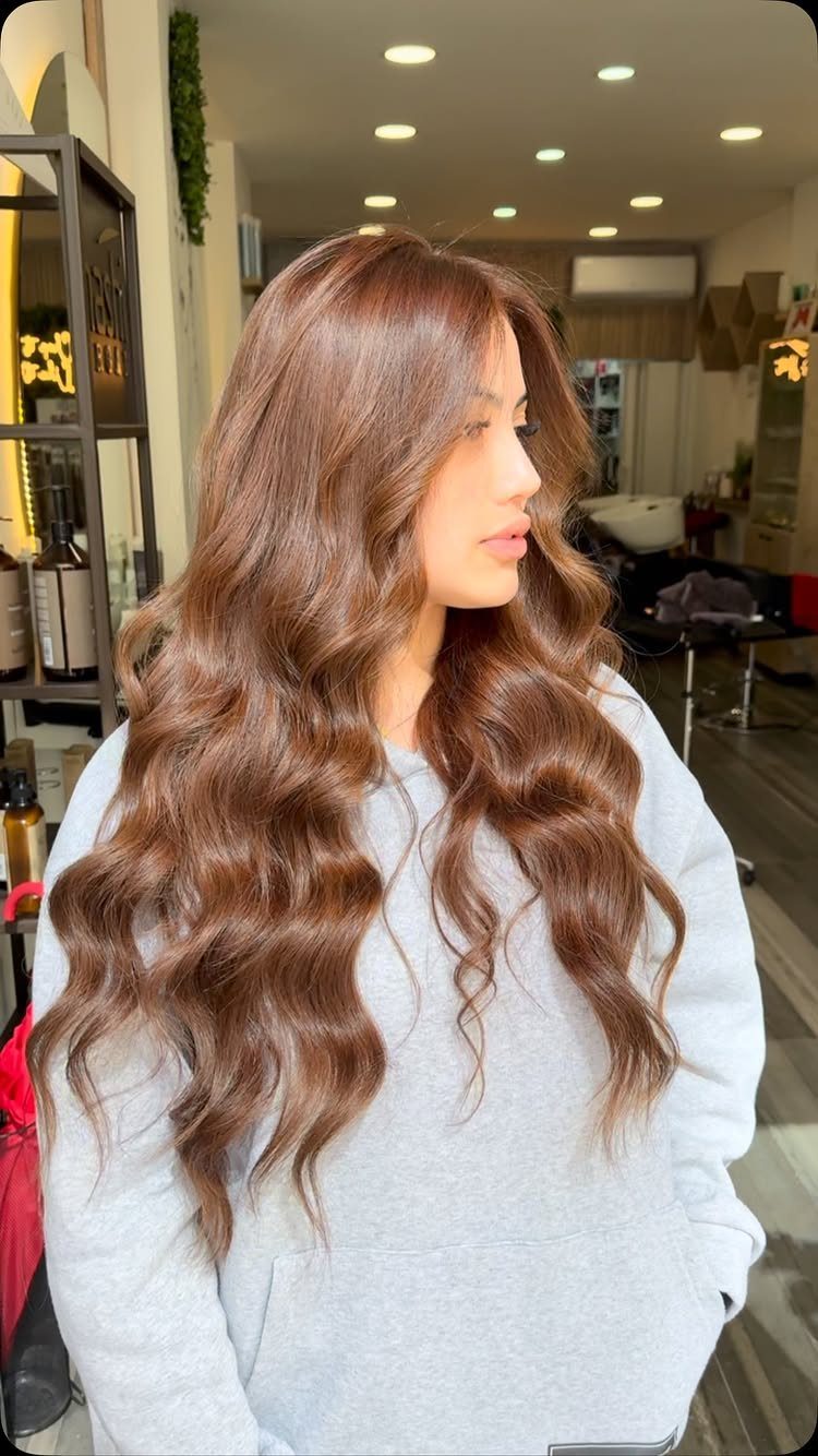 Woman with long wavy caramel brown hair seated in a salon