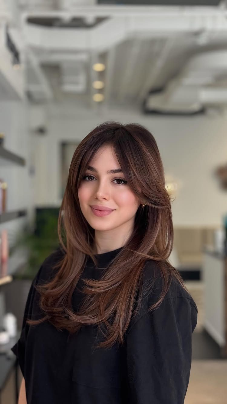 Woman displaying dark brown hair with subtle auburn highlights in a salon