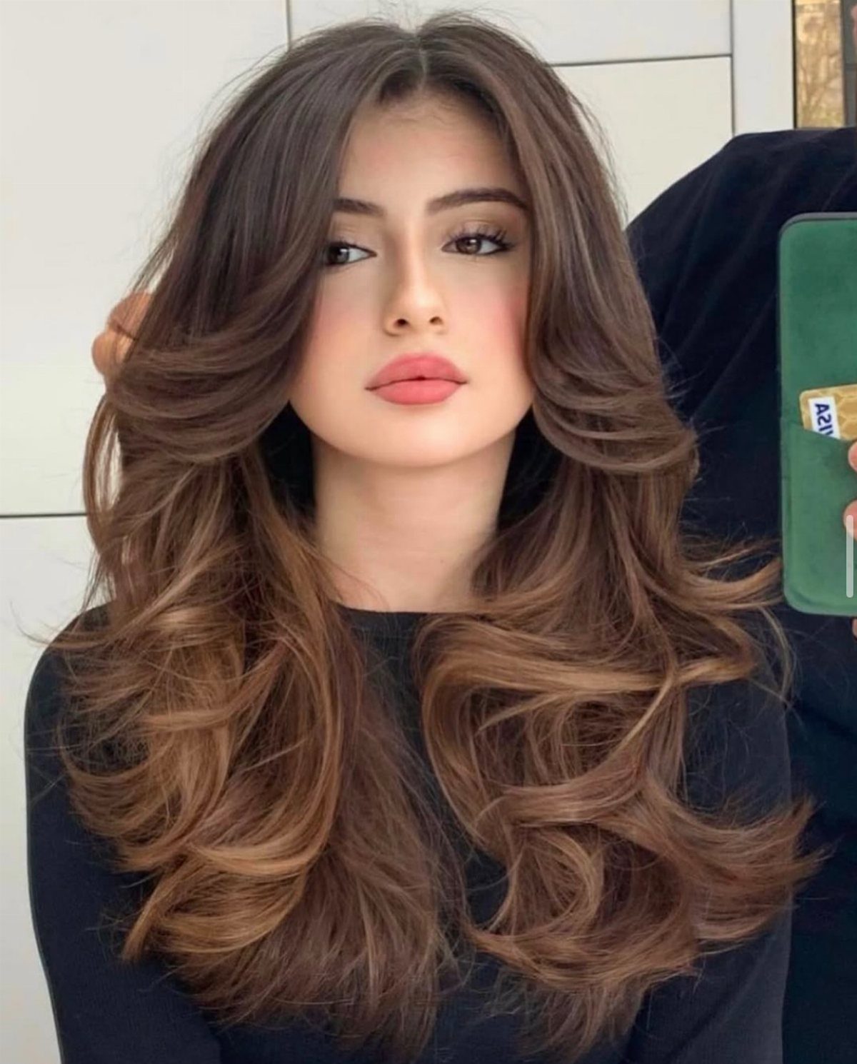Long dark brown hair with golden strands styled in voluminous curled layers