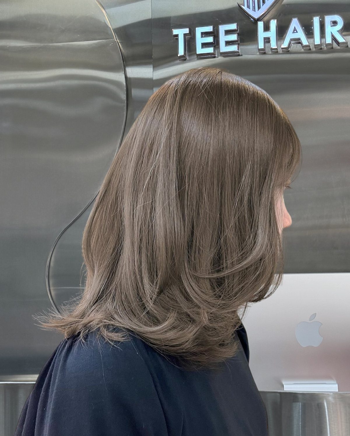 Light ash brown layered hair shown in profile at a salon