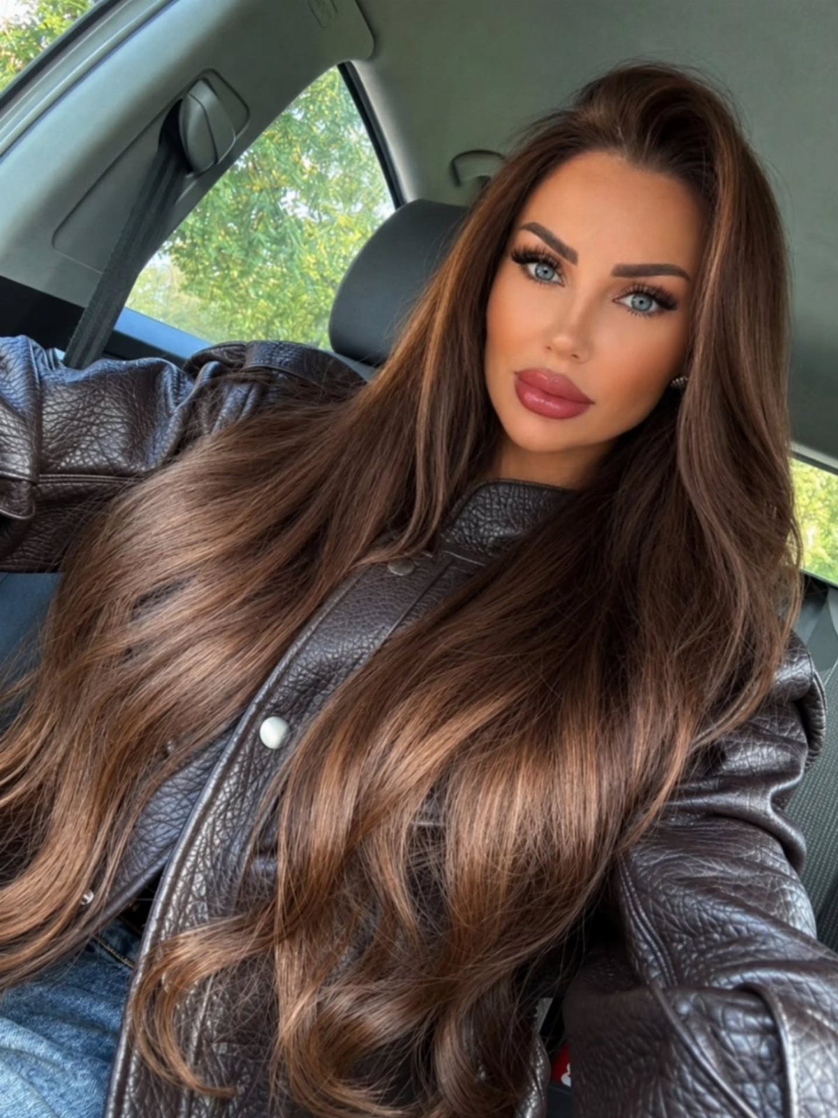 Long wavy brunette hair with lighter dimensional highlights in a car