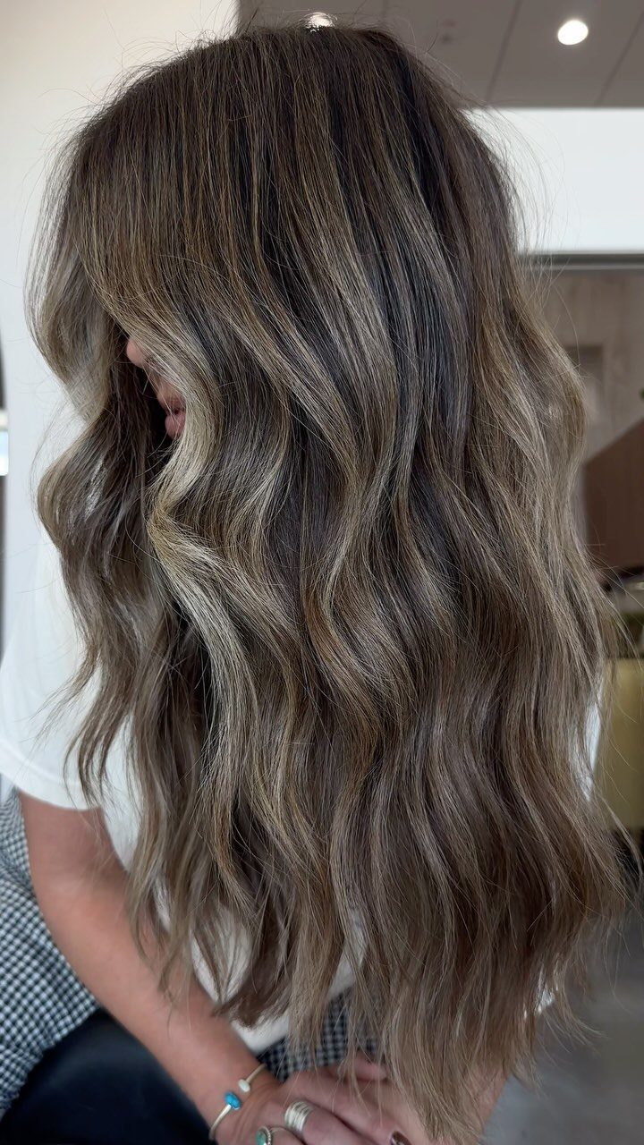 Wavy brunette hair with dark roots and dimensional brown highlights