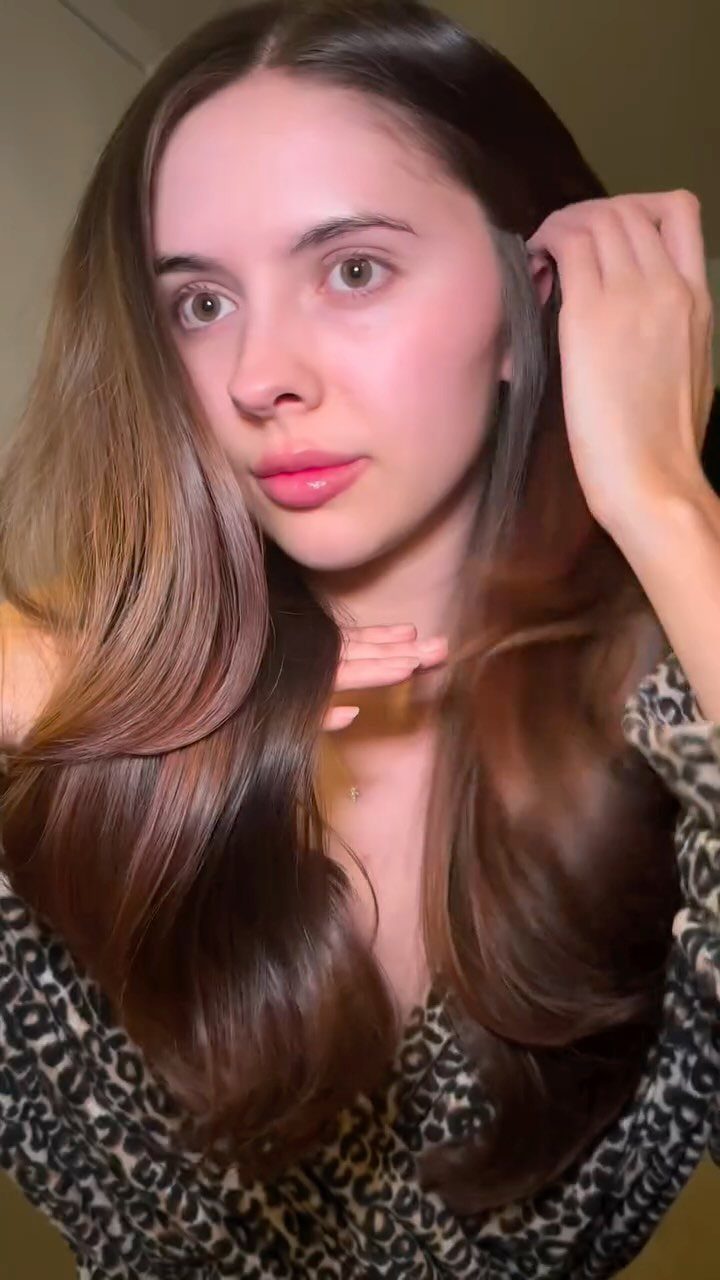 Woman displaying long, glossy dark auburn brunette hair with softly blended warm tones