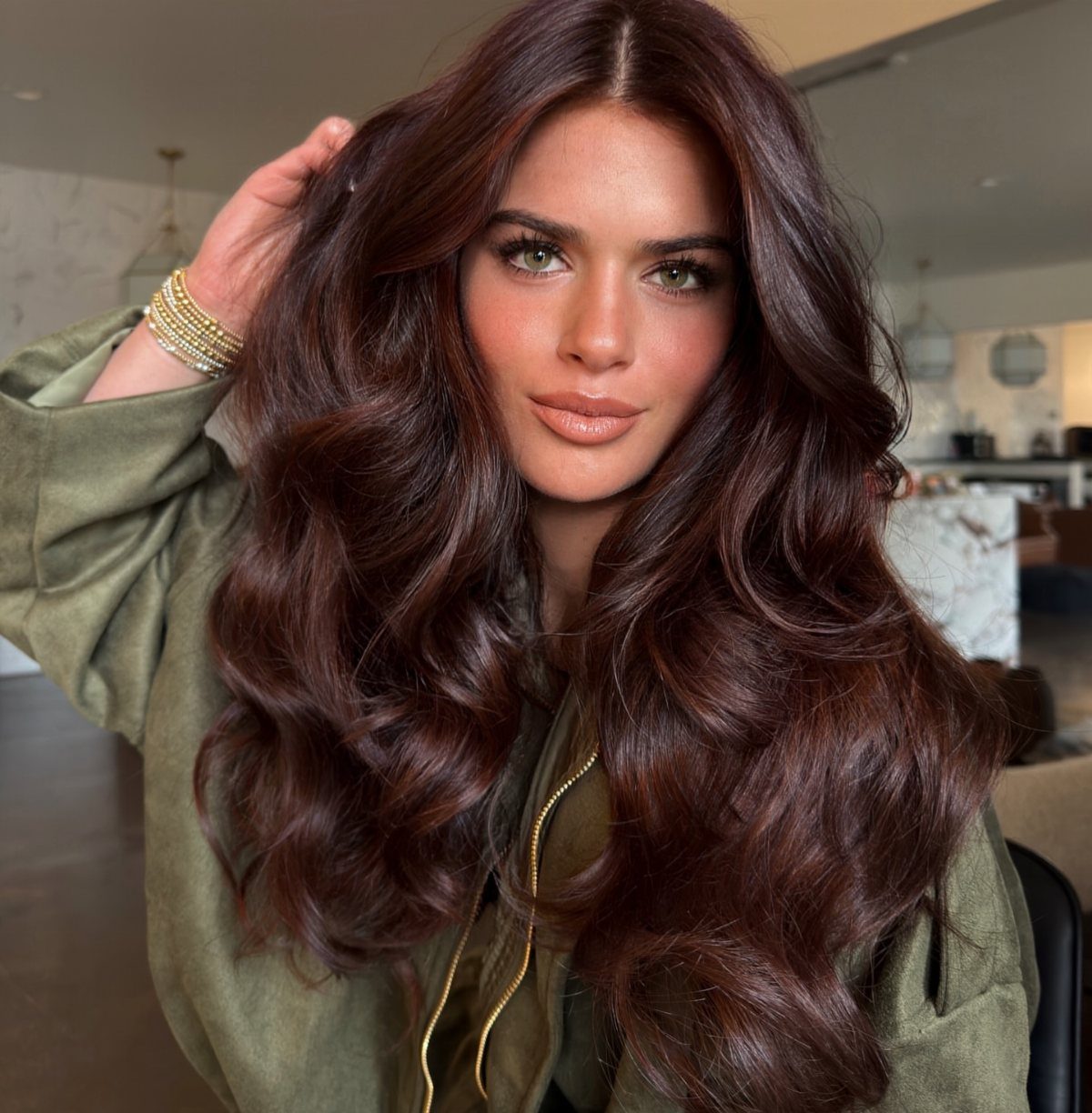 Woman with voluminous dark cinnamon brown hair and warm lighter highlights