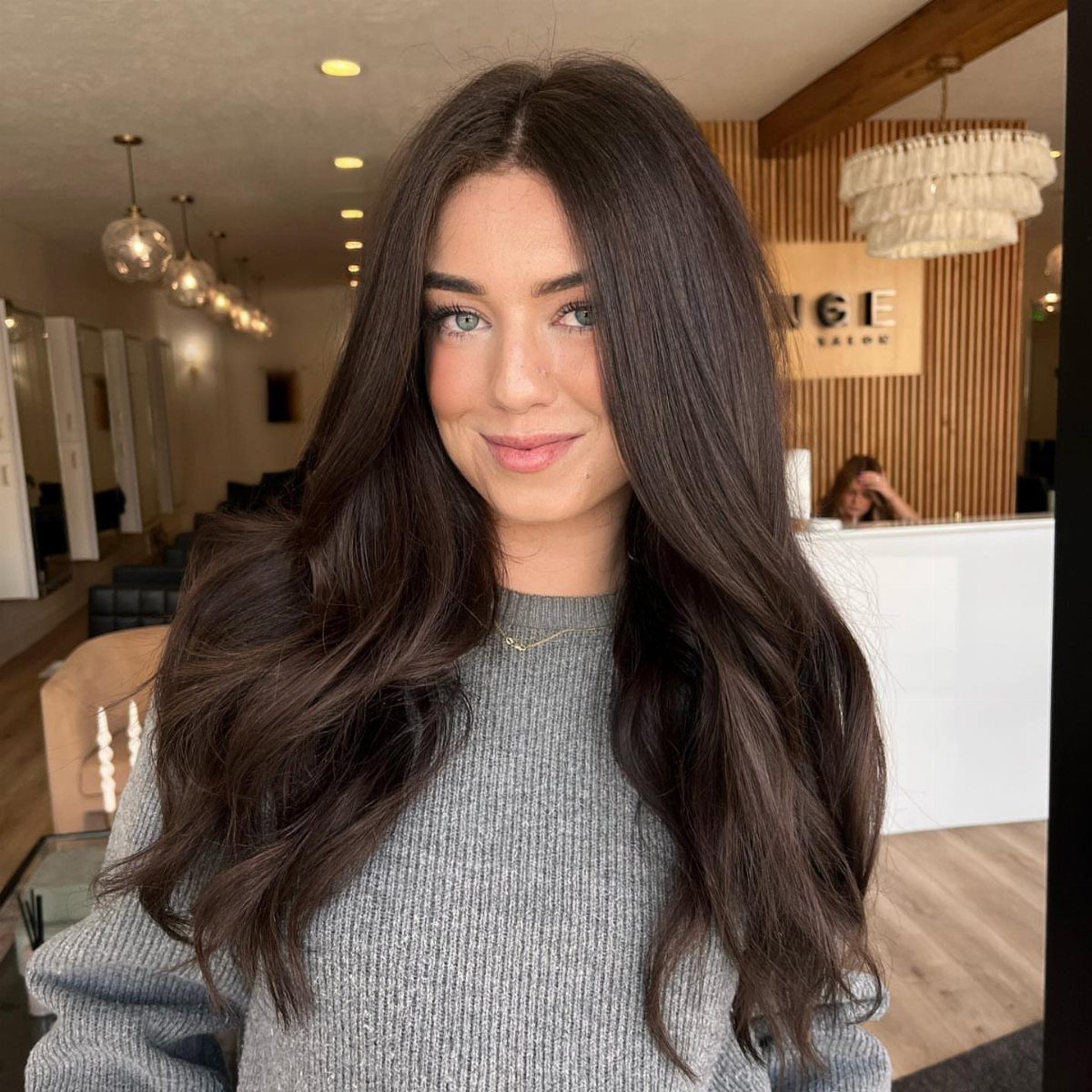 Woman with long, glossy nearly black dark brown waves in a salon