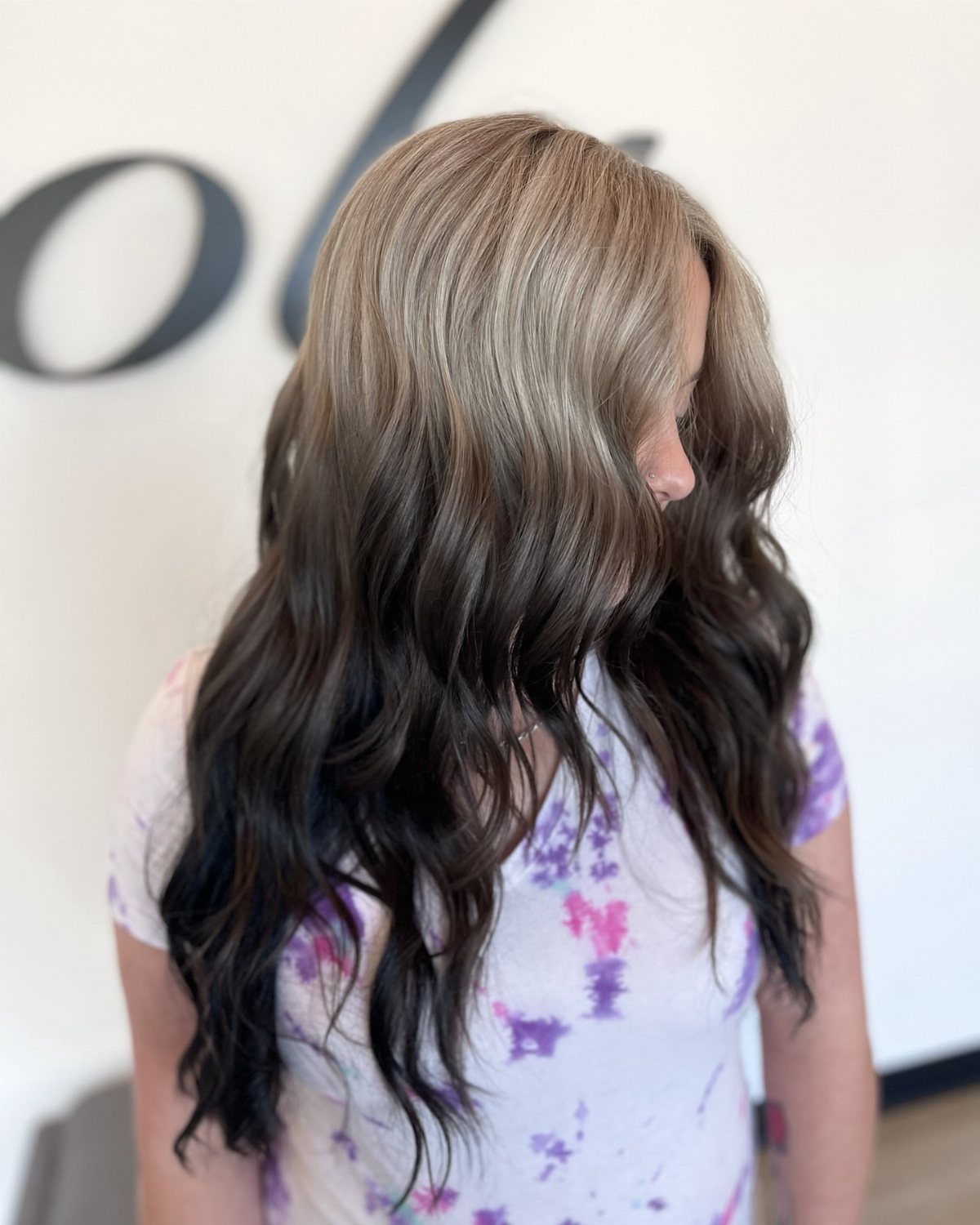 Wavy hair transitions from lighter brown roots to dark brown ends