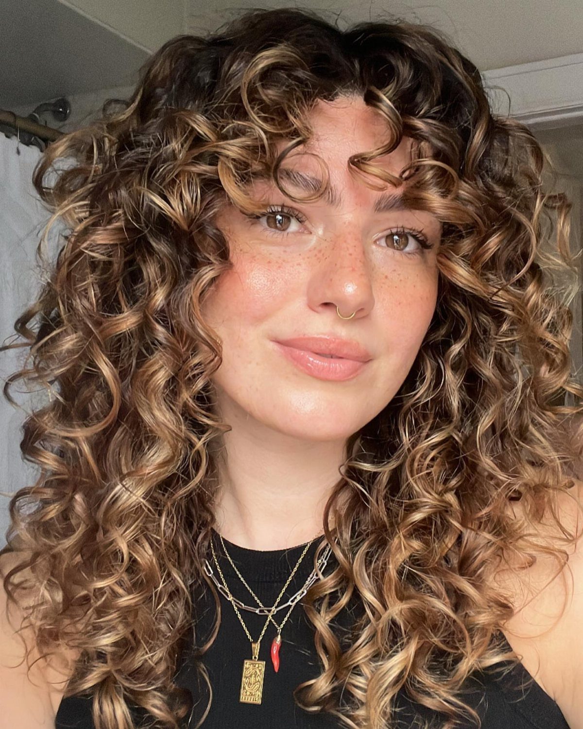 Warm brown curls with a curly fringe frame a person's face