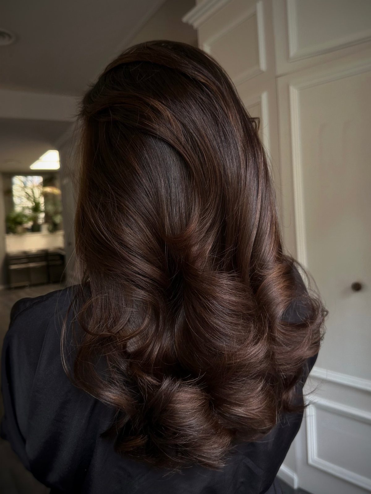 Long dark brown hair styled in glossy, voluminous loose curls