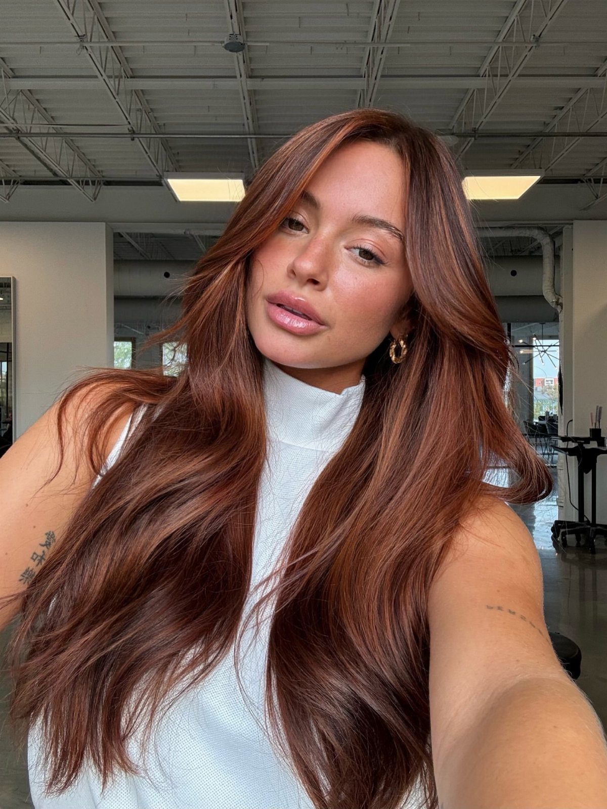 Woman with long, glossy auburn-brown waves posing in a salon