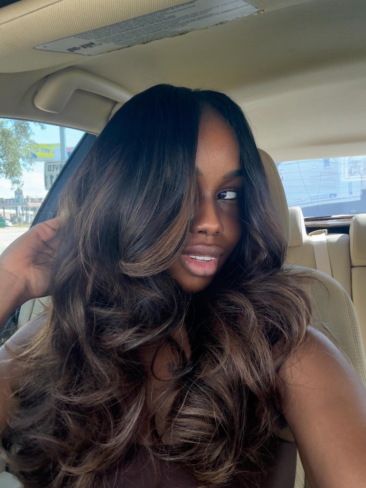 Woman with voluminous dark brown curls and soft highlights framing her face