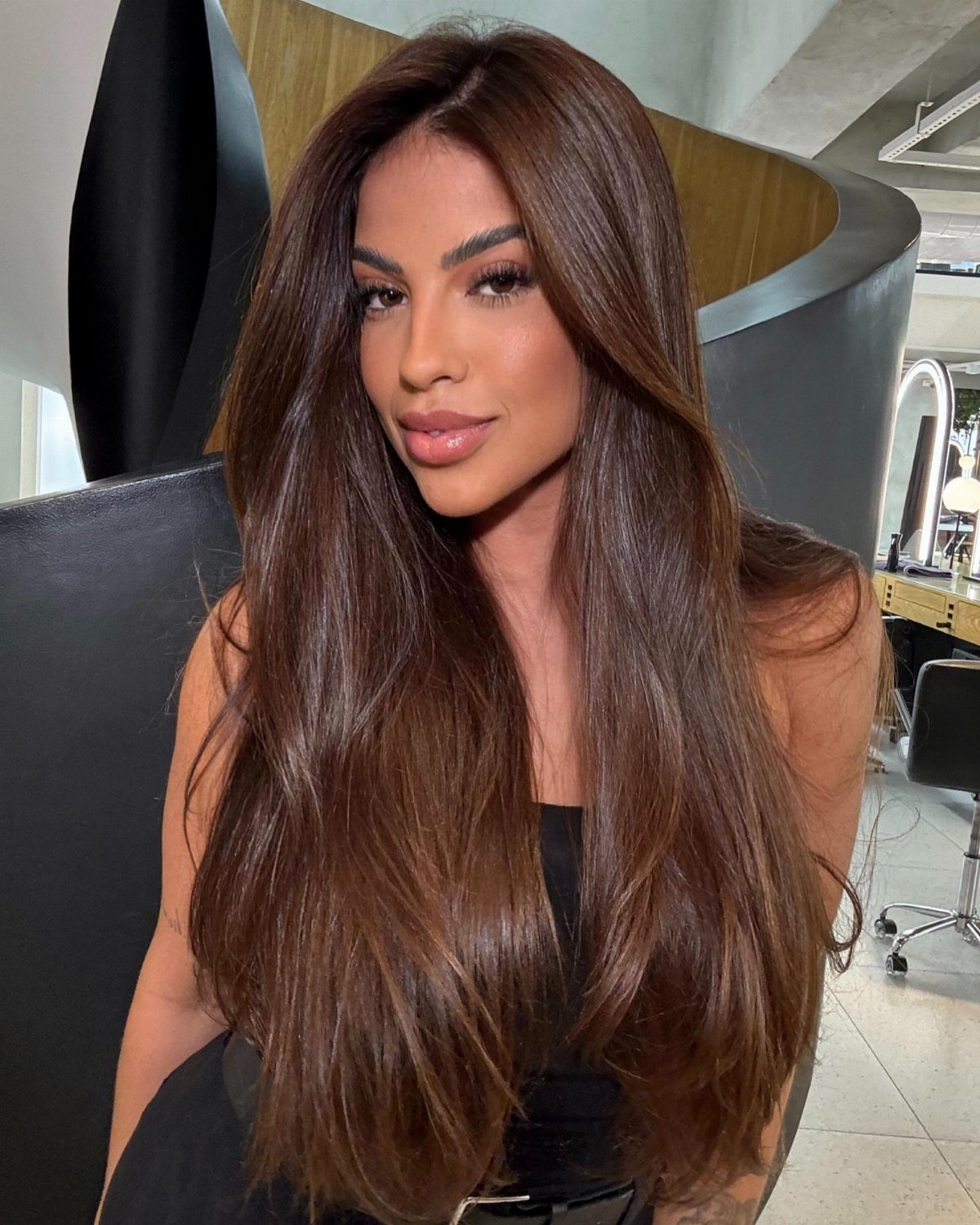 Long, glossy dark chestnut hair with warm copper and golden undertones