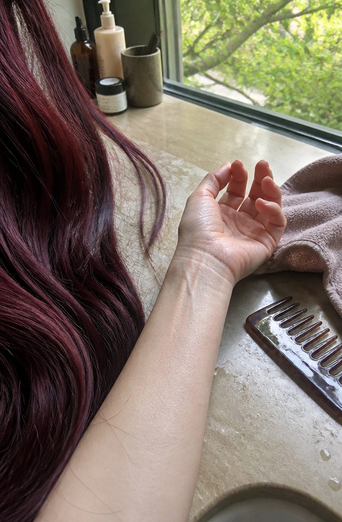 Wrist with blue-purple veins beside cool violet burgundy hair