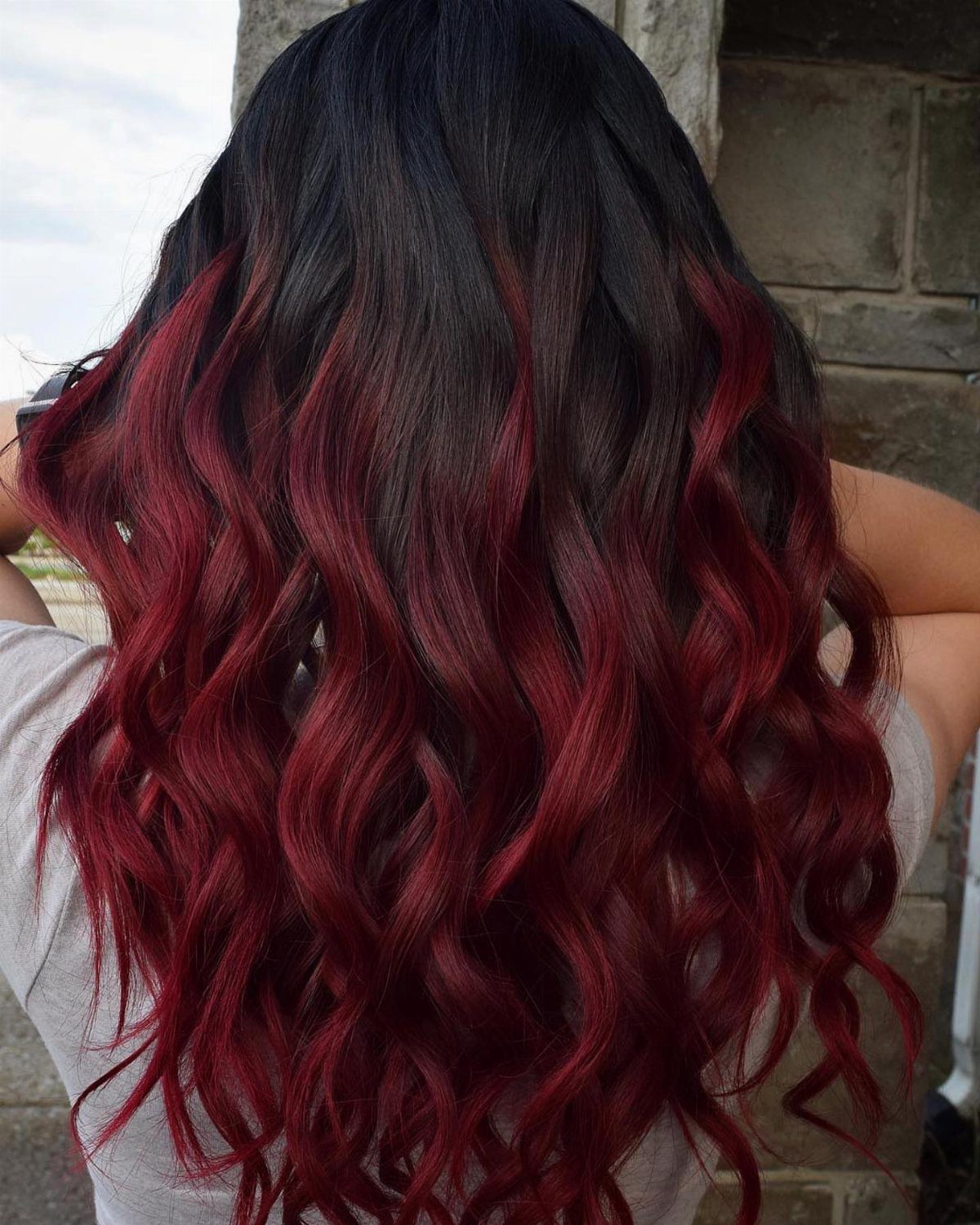 Wavy black hair transitions into deep cherry-red lengths