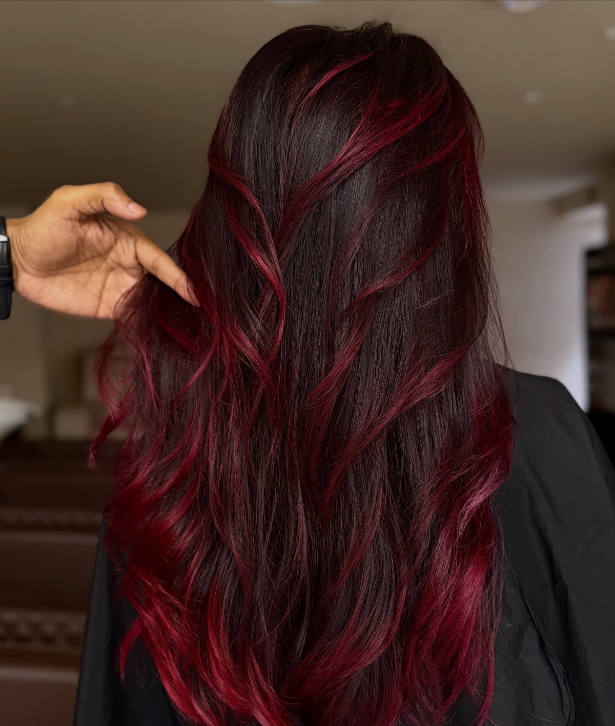 Long deep brown hair with vivid scarlet balayage streaks held apart