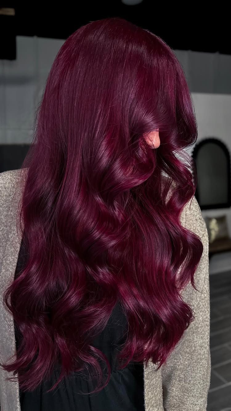 Long raspberry-red curls cascading over a light gray top