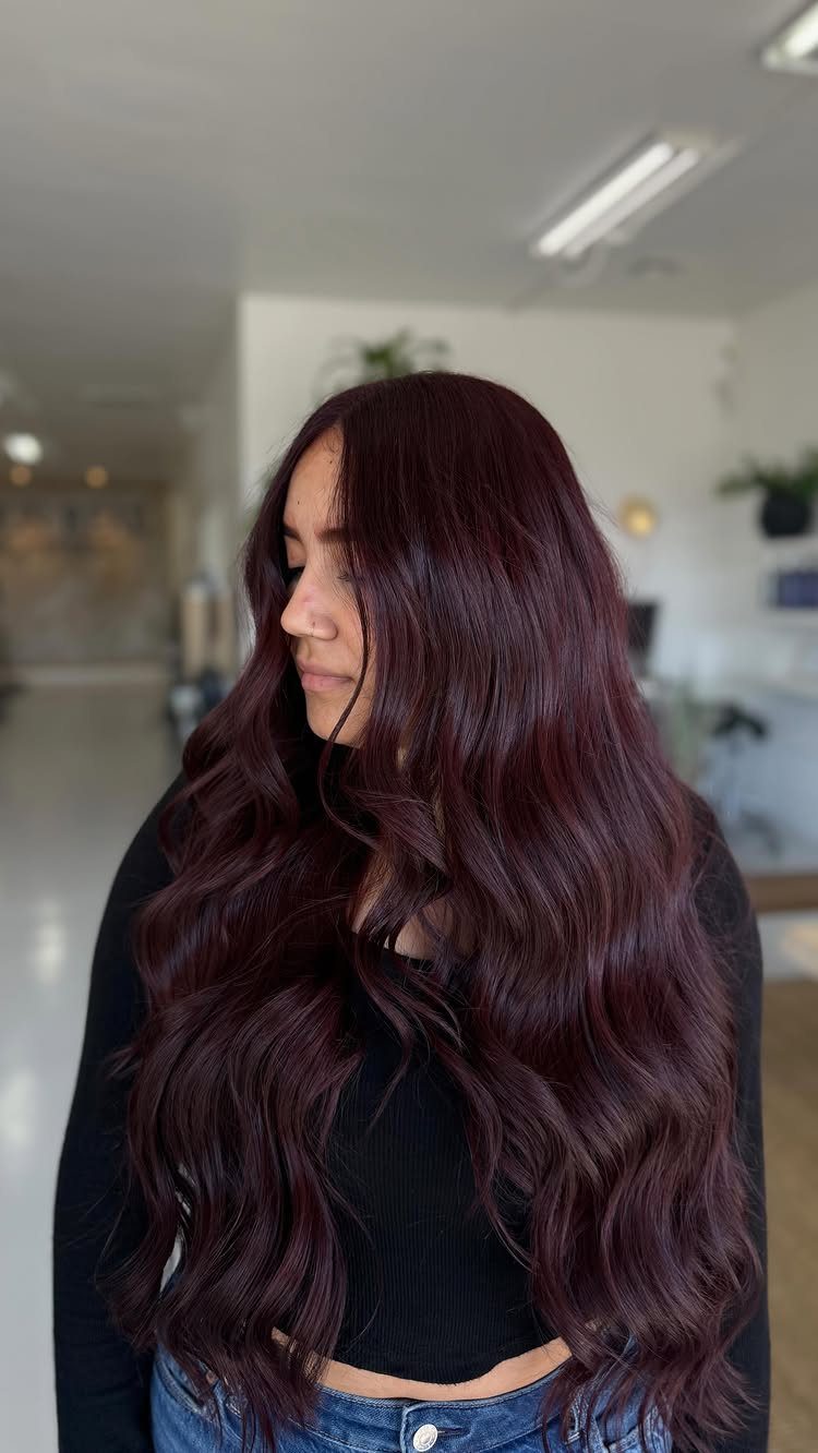 Woman with long, wavy dark mahogany-red hair in a bright indoor room