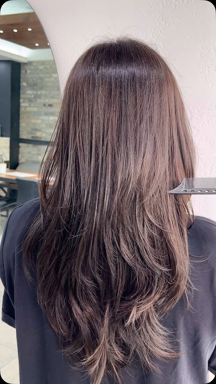 Long wavy ash-brown hair viewed from behind in a salon