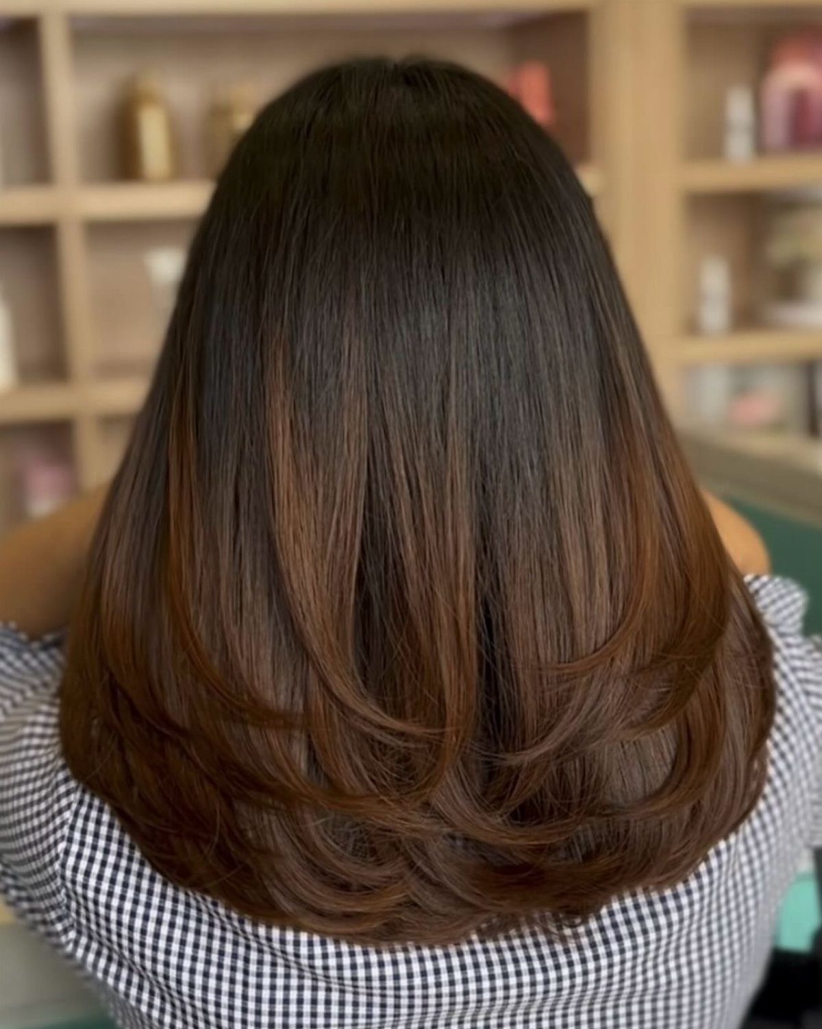 Long dark brown hair shows a subtle transition to softly curled lighter brown ends
