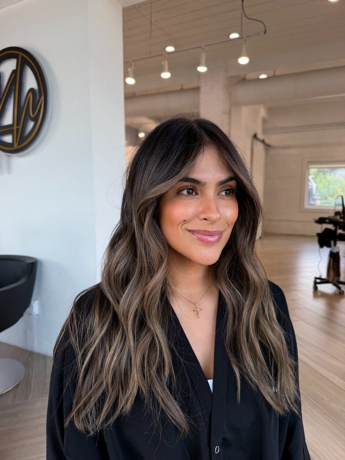 Woman showing long brunette hair with softly blended blonde balayage highlights
