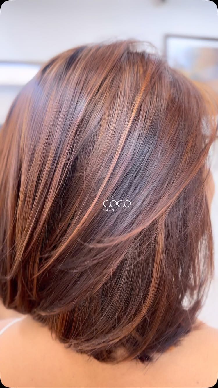 Short dark brown hair with subtle auburn tones in layered strands