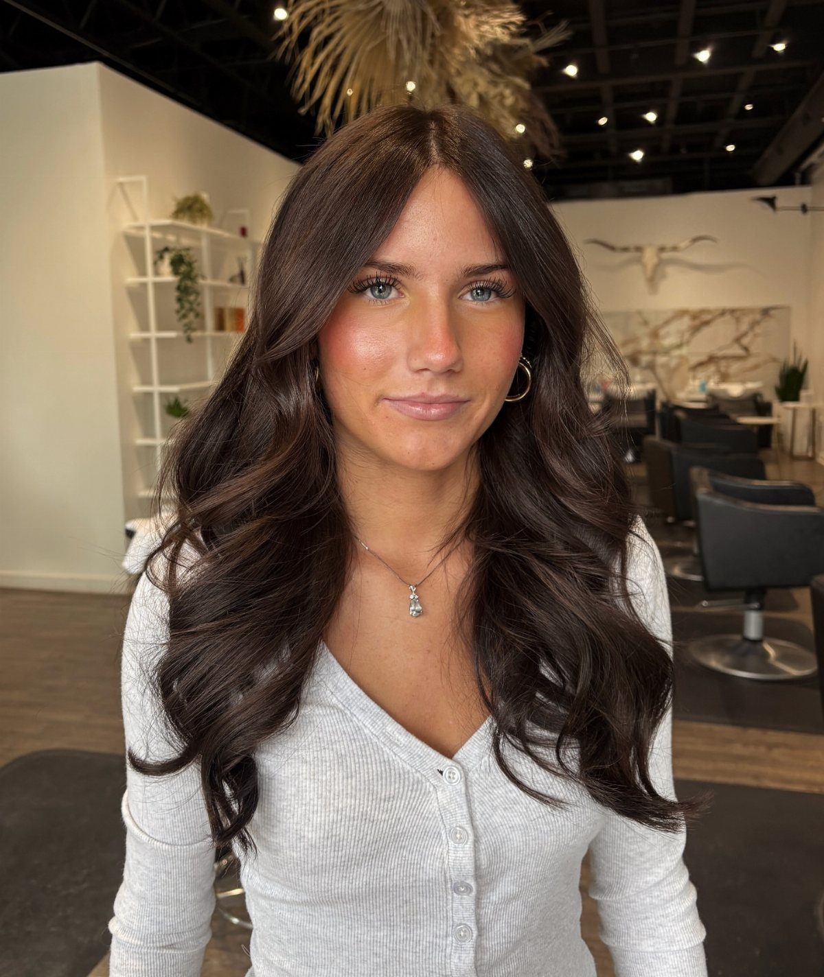 Woman with long, glossy cocoa-brown waves in a salon