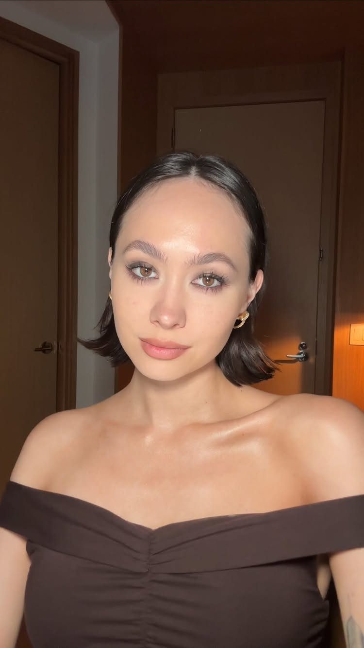 Woman with a sleek dark brown bob, center part, and off-the-shoulder top