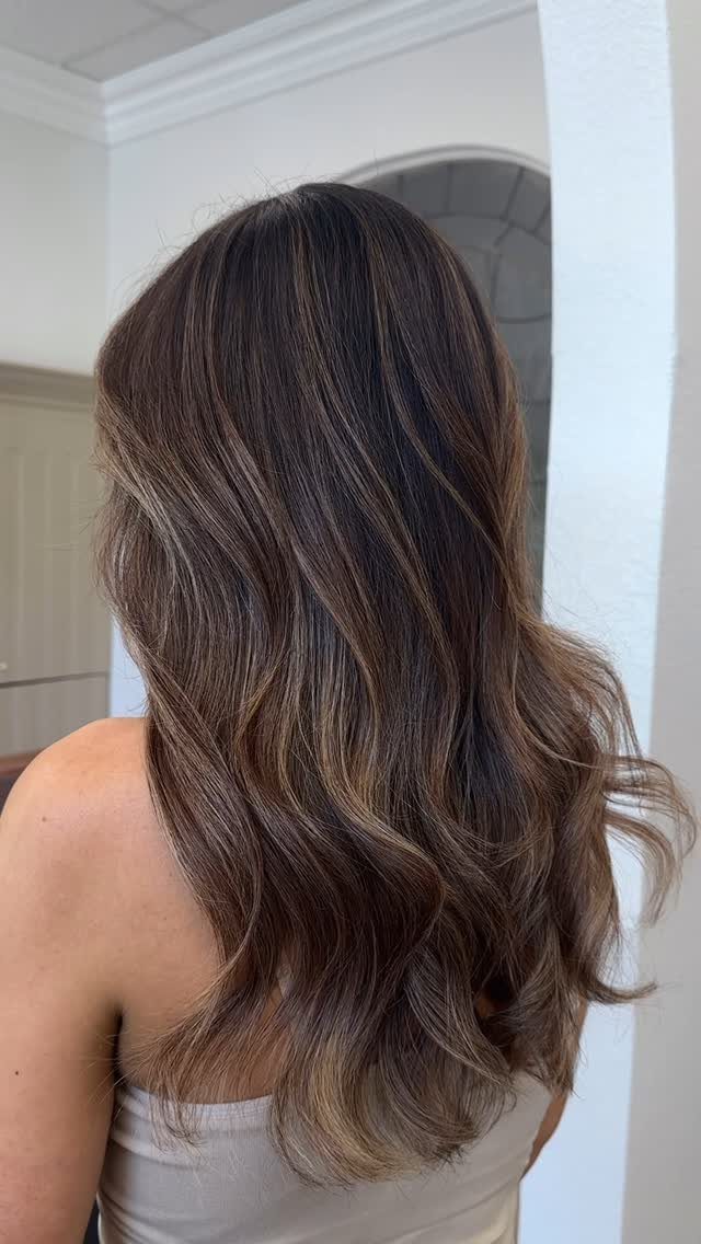 Long wavy brunette hair with fine blonde highlights catching the light