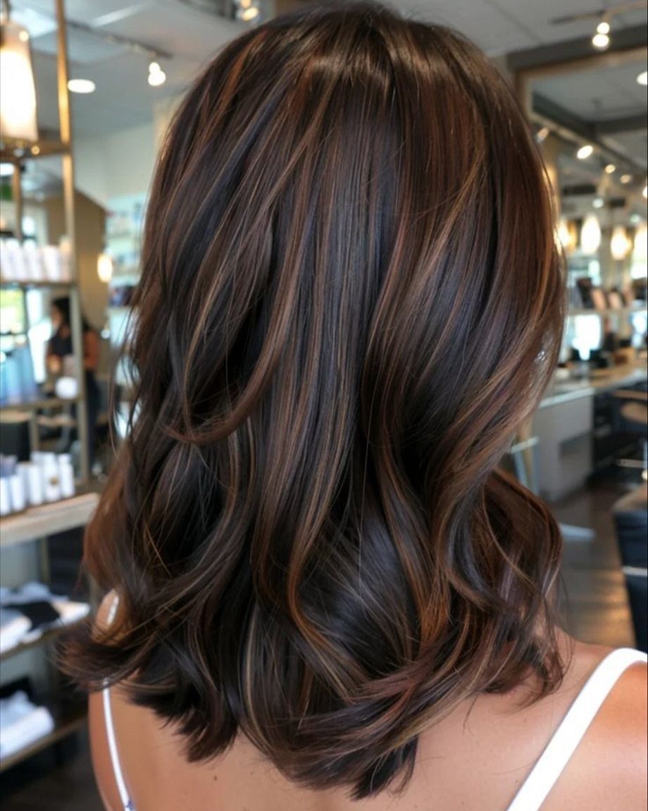 Layered dark brown hair with subtle hazelnut highlights and curled ends