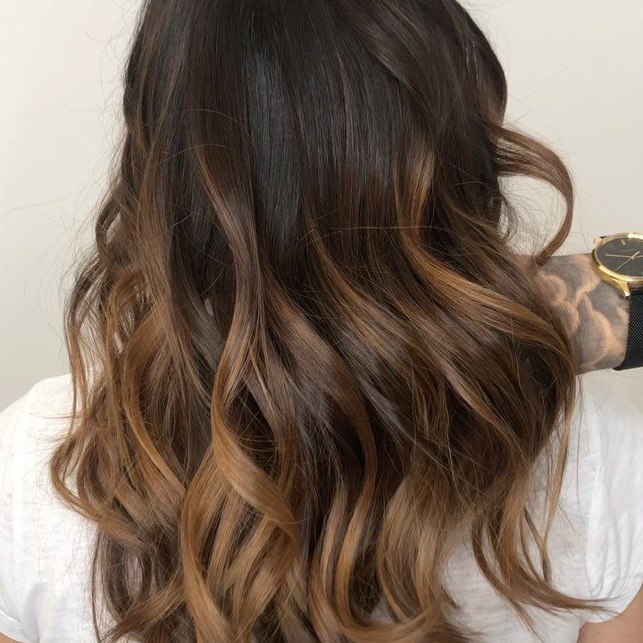 Long wavy dark brown hair blends into warm brown ombré ends