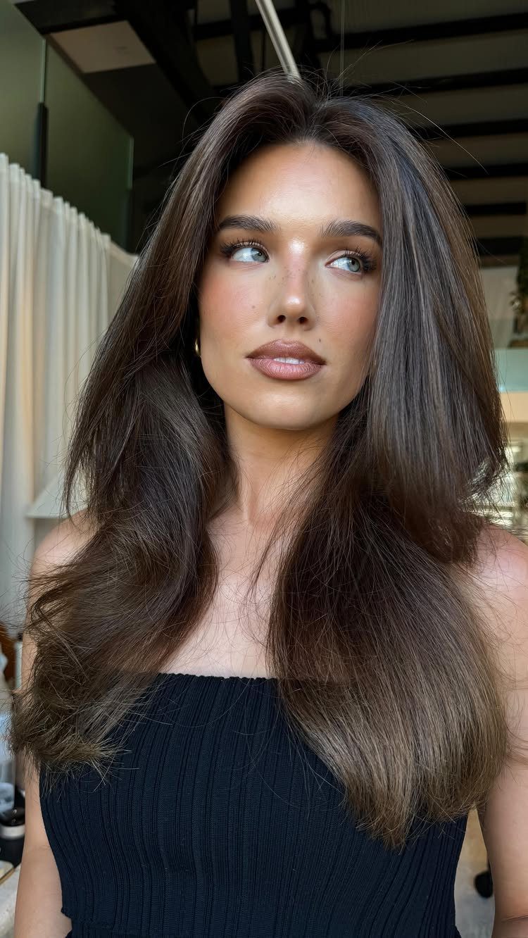 Woman with long neutral brunette hair and subtle, soft highlights