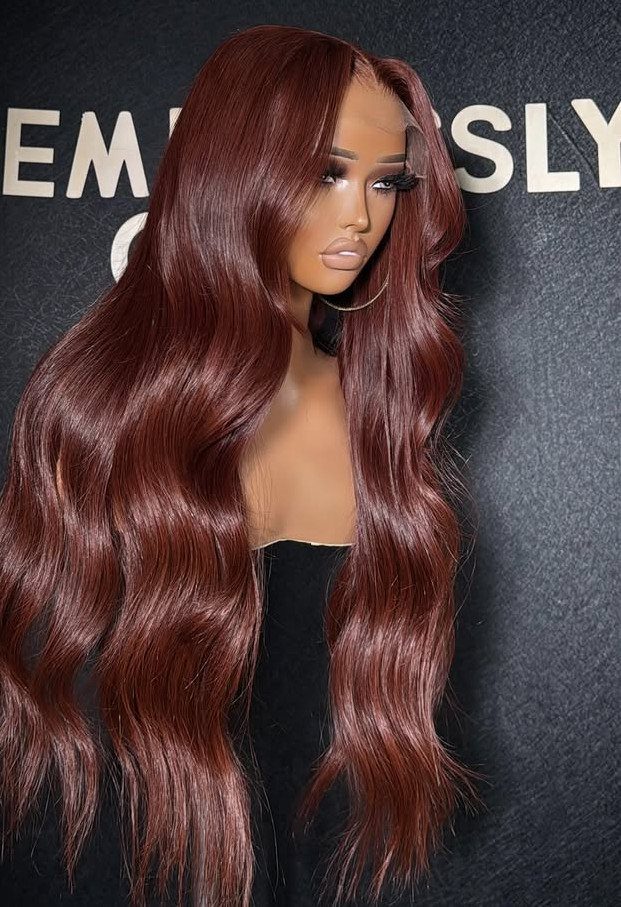Mannequin with long, glossy red-brown hair against a dark lettered backdrop