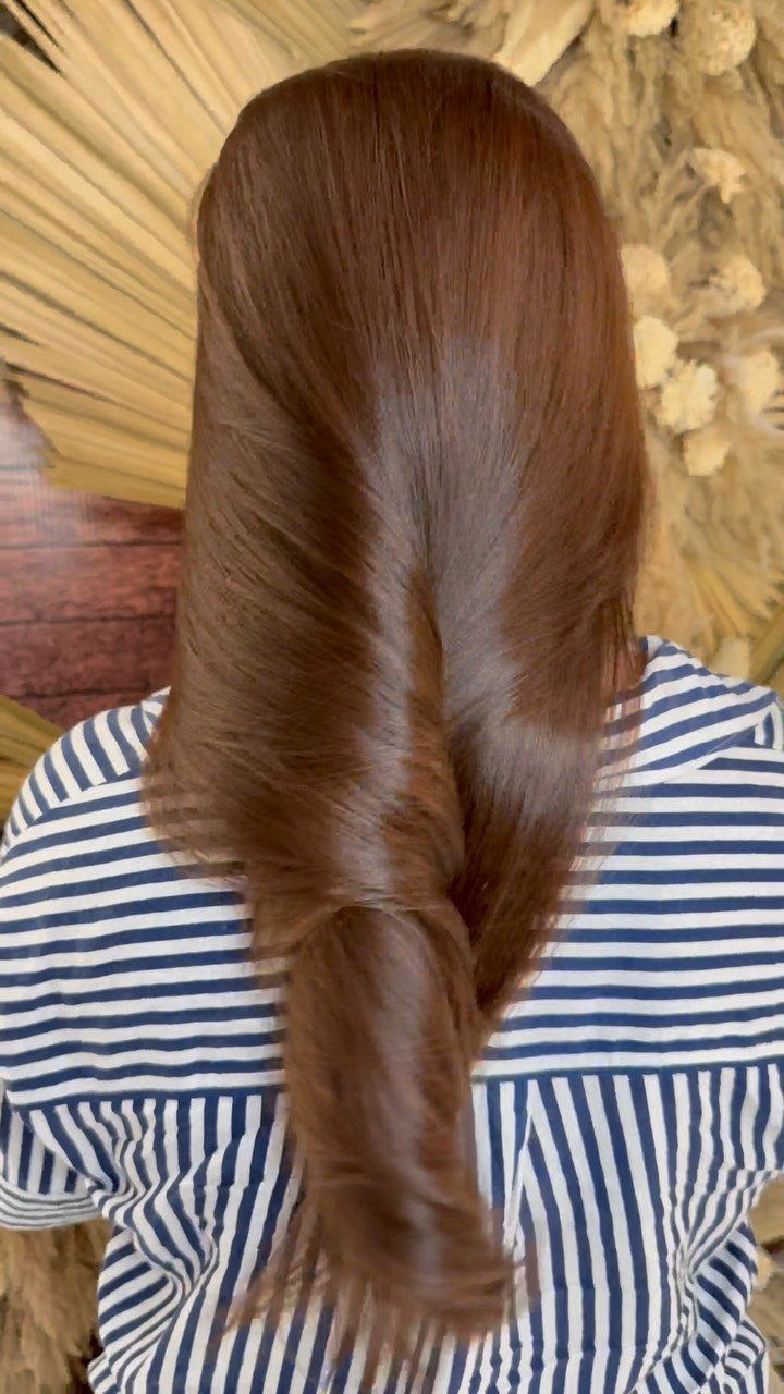 Long smooth brown hair gathered into a loose twist over a striped shirt