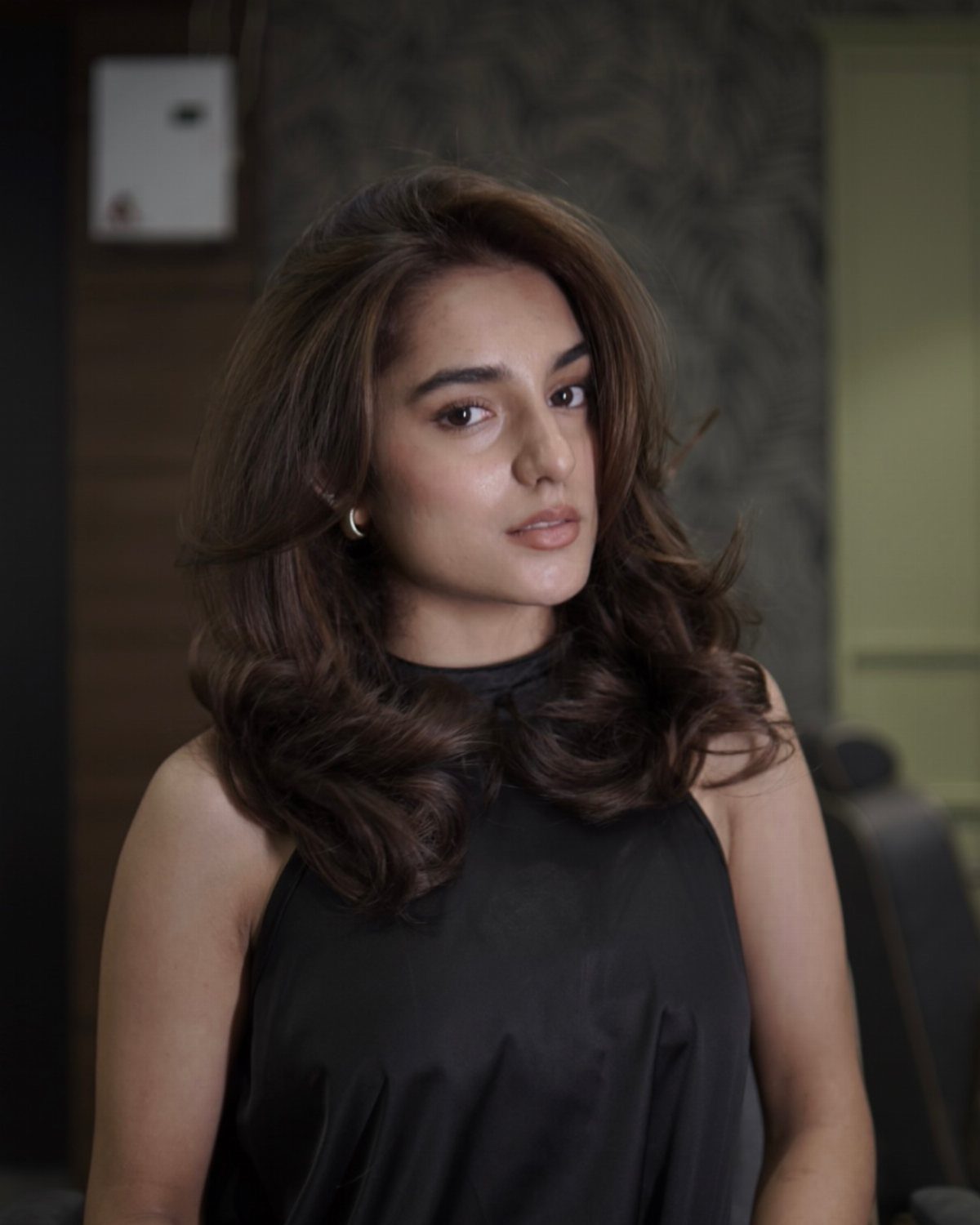 Woman with long dark brunette hair showing soft curls and understated warm dimension