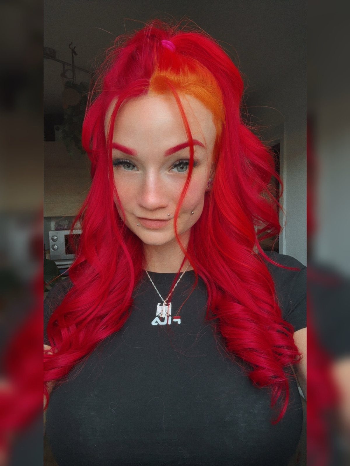 Person with long vivid red hair and an orange-red section at the crown