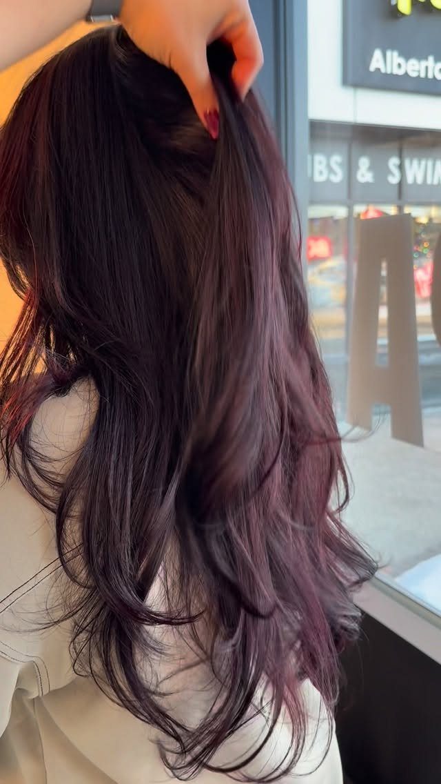 Long dark red-brown waves held up near the crown by a hand