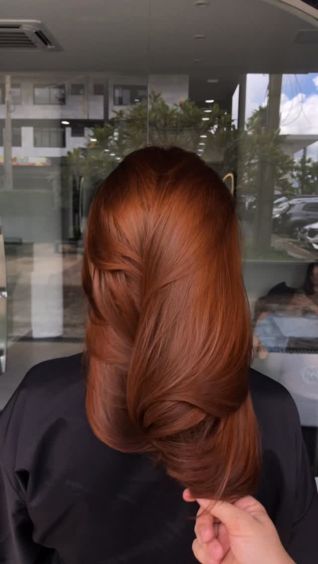 Light auburn hair styled in a glossy, loose twisted braid