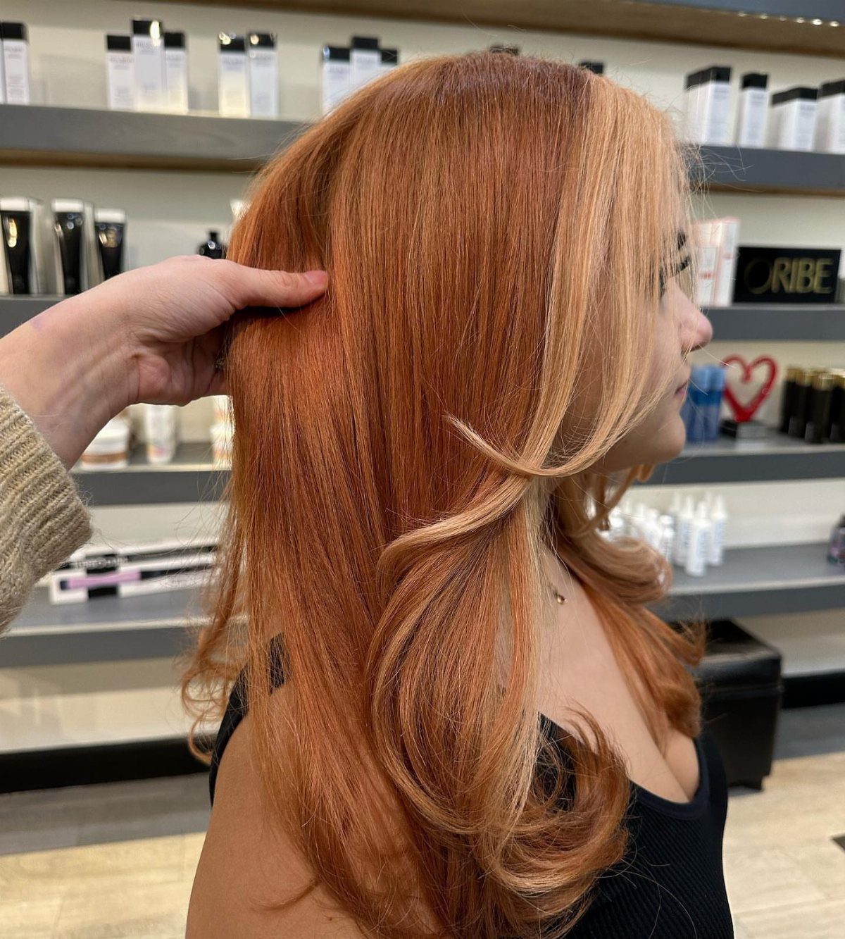 Copper-red curls with bright copper strands framing the face in a salon